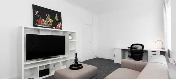 modern bedroom with white walls and bedding featuring a television stand and artwork showcasing six vibrant colors